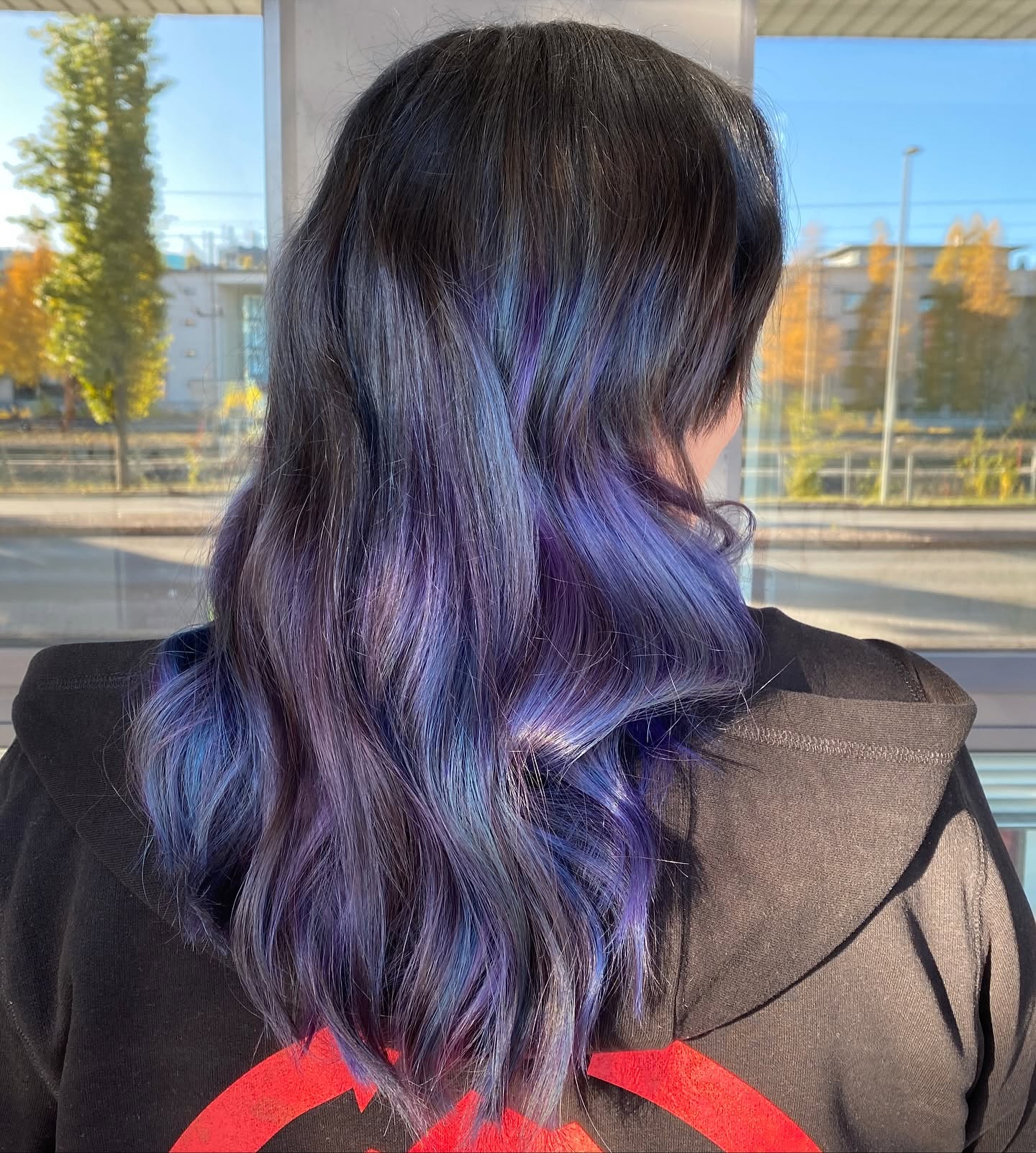 Pitkät tummat hiukset, joissa violetin ja sinisen sävyisiä raitoja.