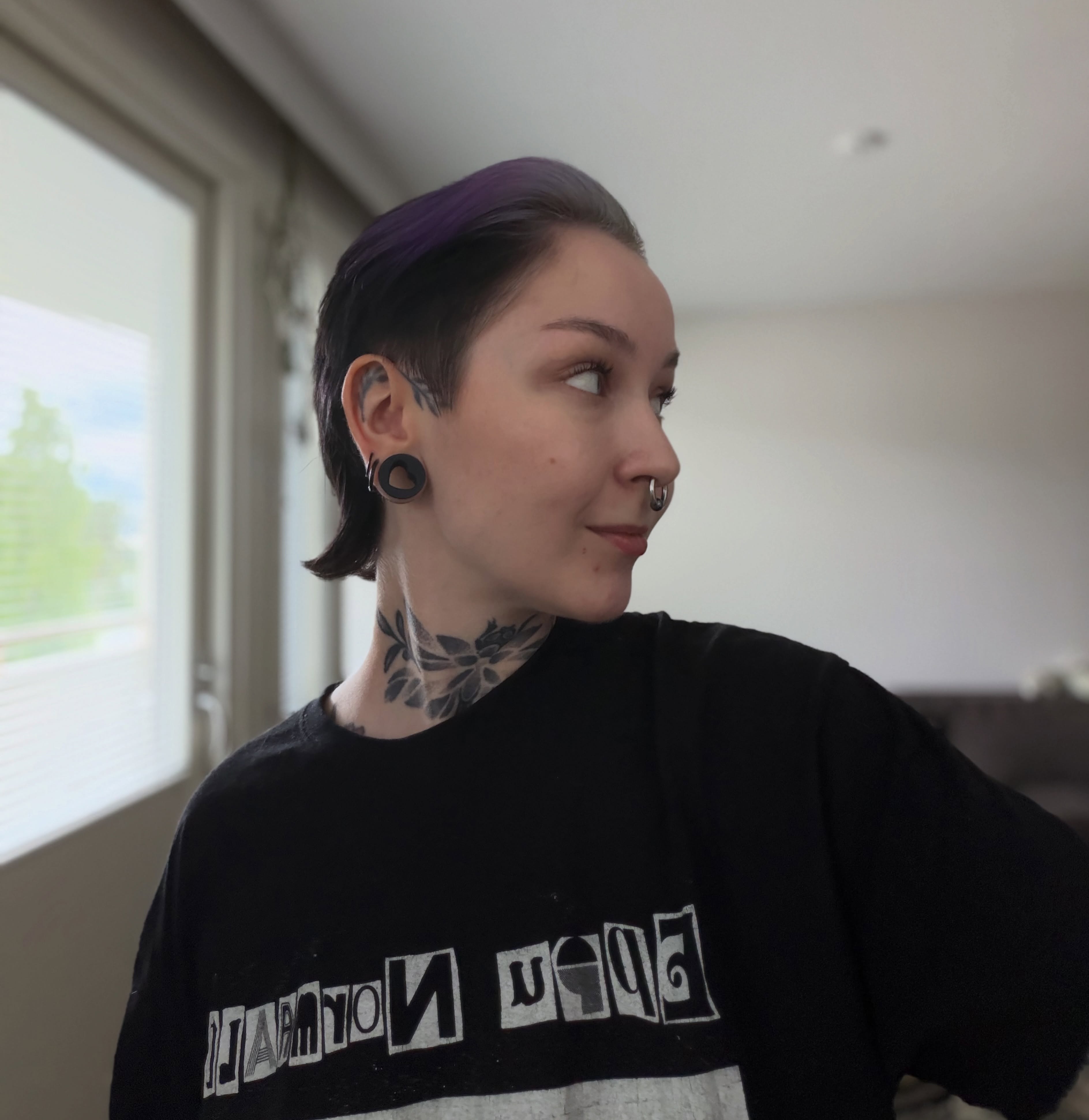 Asiakas sivulta kuvattuna: lyhyt, sivuilta ajeltu leikkaus ja violetiksi värjätty tyvi.